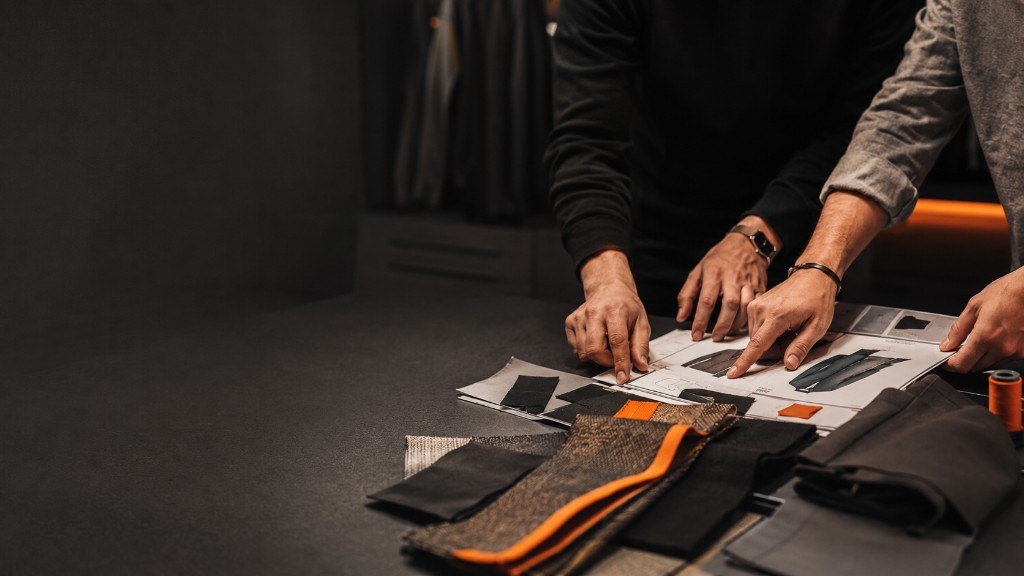 HAIZAINTL team reviewing a tech pack, fabric swatches and trims on a studio table