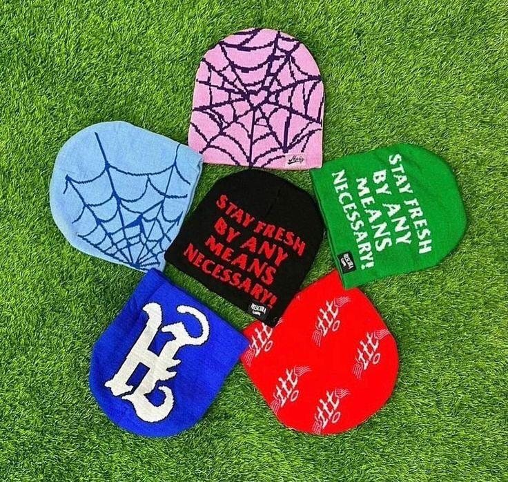 Assorted custom jacquard knit beanies with text and logo patterns on turf